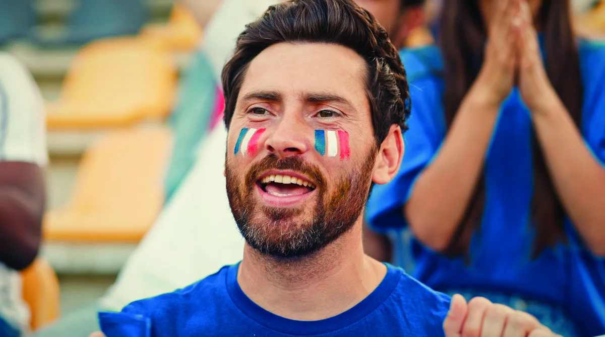 Un supporter au visage peint aux couleurs de la France, dans une tribune.